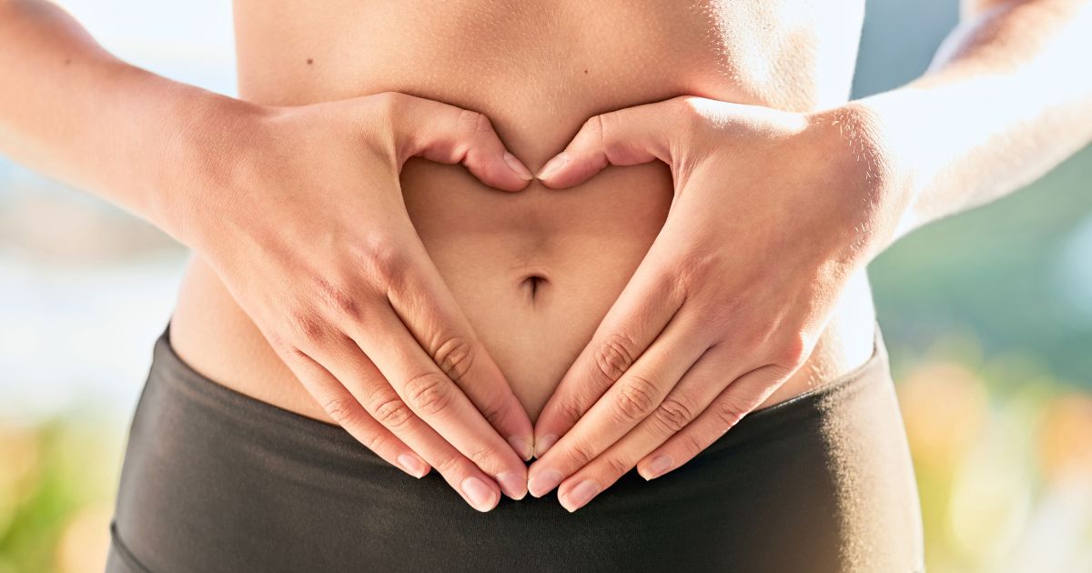 健康的なお腹に両手でハートマークを作っている人物。