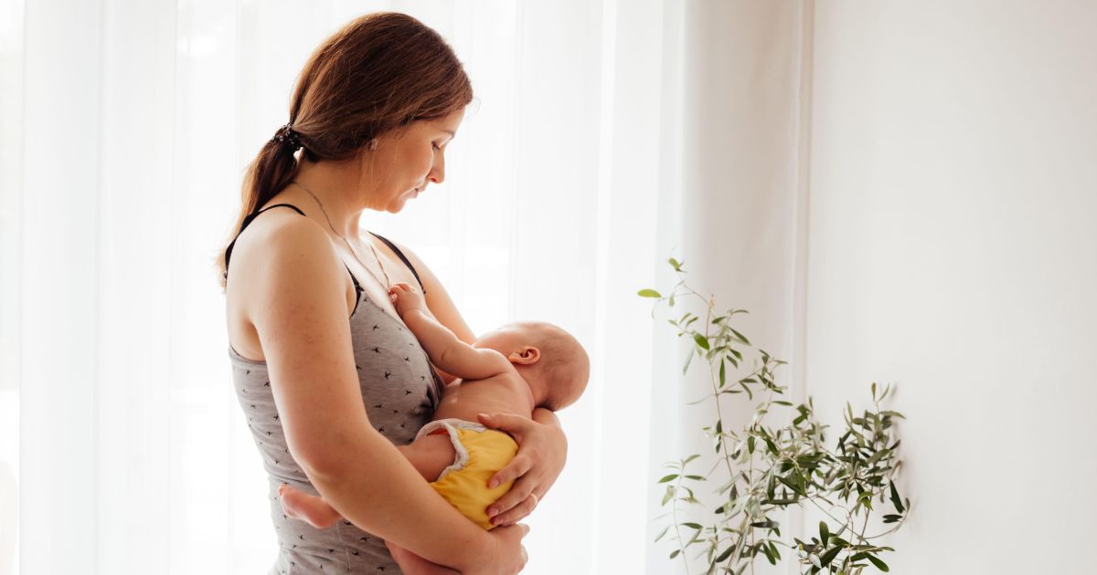 赤ちゃんを優しく抱っこして授乳している母親。